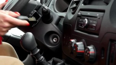 Parlak kırmızı manikürlü bir kadının yakın çekimi arabanın anahtarlarını prize sokar ve motoru çalıştırır. Araba kontağı. Anahtarı çeviriyorum..