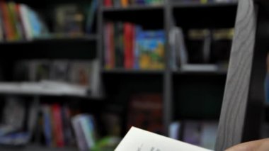 Kameranın kaydıraktaki hareketi, sayfayı çevirirken kitabın yakın çekimi. Kütüphanede, bir kız ya da bir erkek bir kitap okuyor, sayfayı çeviriyor. B-kaydı video geçişi.