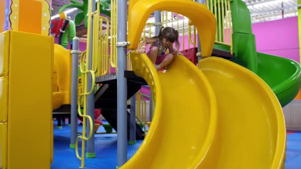 Een Vrolijk Klein Meisje Glijdt Van Een Plastic Glijbaan Speelkamer — Stockvideo