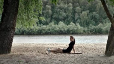 Güzel bir kız kumlu bir sahilde uçan kavak kürkünün arasında otururken hayal kurar. Nehrin arka planında bir kadının olduğu çok güzel, muhteşem bir video..