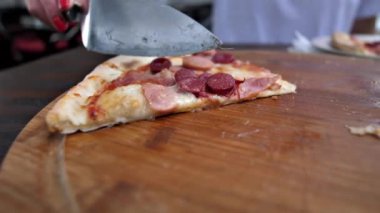 Kızın metal bir pizza küreğiyle aldığı taze pişmiş lezzetli pizzanın yakın çekimi. Yemek ve 4k 'lık görüntüler. Kahvaltı, öğle ya da akşam yemeği restoranda, kafede ya da pizzacıda..