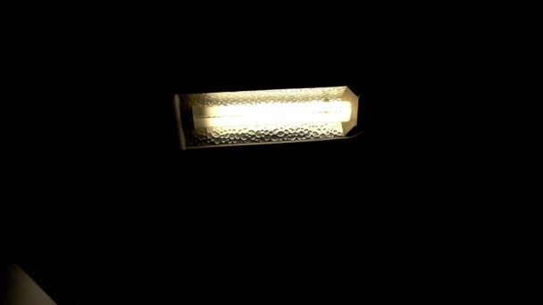夜の暗い部屋でオンとオフを切り替える省エネ蛍光灯とテーブルランプのクローズアップ — ストック動画
