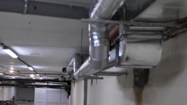 Bir ofis binasının veya konut binasının inşası veya yenilenmesi sırasında yeni bir havalandırma sistemi. Havalandırma kanalının yenilenmesi. Tavanda krom kaplı büyük borular var..