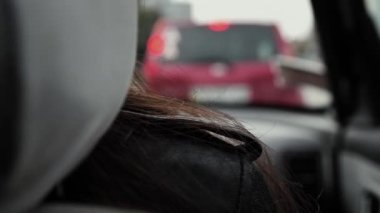 Bir arabanın yolcu koltuğunda oturan bir kızın omzundaki saçın yakın çekimi. Trafik sıkışıklığında uzun süre bekledik. Şehir trafiği, aşırı kalabalık caddeler..