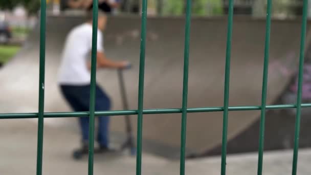 Arkasında Çocukların Kaykay Parkında Kaykay Scooter Sürdükleri Çitlere Odaklan — Stok video