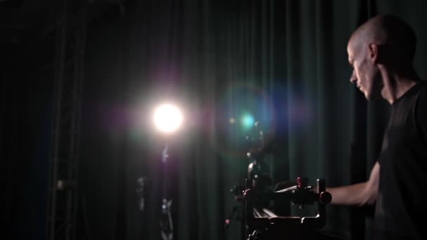 テレビチャンネルの男性カメラマンは スライダーを使用して テレビスタジオでトークショー ニュース コンサートのビデオを撮影します ビデオグラファーは プロのスタジオ照明の下でビデオコンテンツを撮影します — ストック動画
