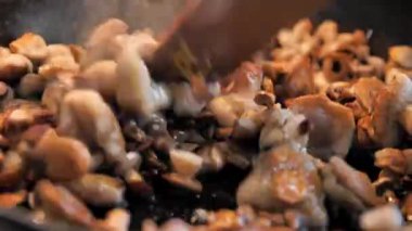Aşçı tavada soğanlı mantar kızartır, ahşap spatulayla karıştırır. Ev mutfağı. Kızarmış tereyağlı mantar. Geleneksel yemek. Ev hanımı lezzetli bir şeyler hazırlar. İştah açıcı kızarmış mantar..