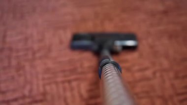 POV odayı temizlerken ilk kişi görüntüsü. Elektrikli süpürge tüpü ve yerleri süpürmek için fırça..