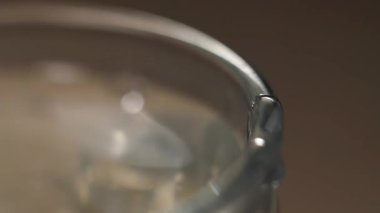 Süper yavaş çekim videosunda bir bardak suyun kenarına düşen aşırı yakın çekim makro görüntüsü..