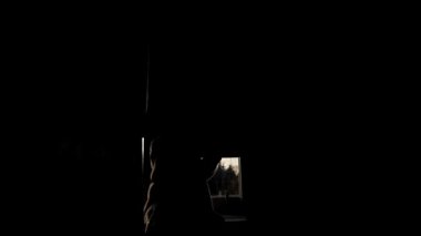 Pencerenin perdelerini ya da perdelerini açan arka plandaki genç kızın silueti. Işık odayı dolduruyor. Kız pencerede otururken rüya görür. Çocuk sabah perdeleri açar..