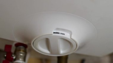 Adam ısıtıcı termostat modunu değiştiriyor ve ısıtma göstergesi ışığı sönüyor. Elektrikten tasarruf etmek için bir adamın eline yakın çekim yapmak elektrikli su ısıtıcısını kapatır. Enerji ve ekonomik kriz.