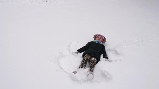 Маленька Дівчинка Робить Сніговий Ангел Щаслива Дитина Лежить Снігу Розважається — стокове відео