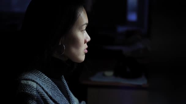 一个漂亮的亚洲女孩晚上在一个黑暗的房间里的电脑上工作 房间里点着台灯 年轻的女职员正在打字 在线处理文档 夜间工作 — 图库视频影像