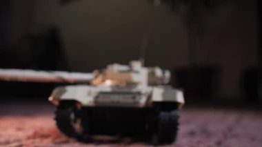 İzole edilmiş uzaktan kumandalı bir oyuncak tankın yakın plan çekimi tareti döndürür ve namludan ateş eder. Askeri çocuk oyuncakları. Ağır silahlarla bir savaş oyunu. RC oyuncak tankı
