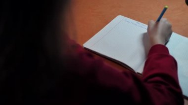 Kız öğrenci ev ödevi yazıyor. Öğrenci evde ders öğrenir. Yurt içi öğrenim.
