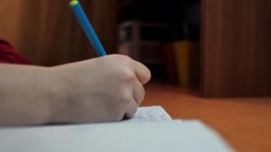 Kız öğrenci ev ödevi yazıyor. Öğrenci evde ders öğrenir ve bir not defterine bir kalemle yazar. Mesafe iç eğitim.