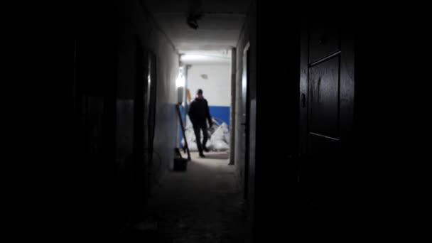古い放棄された建物の廊下を歩く見知らぬ人のゆっくりとした動きのシルエットがドアにやってきて開きます バックリットマンは長い部屋を歩いている 人間の影 — ストック動画