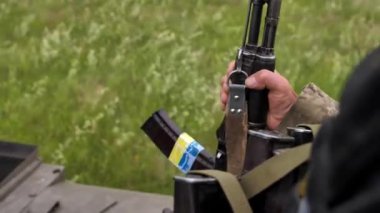 Ukrayna Silahlı Kuvvetleri 'nin askeri Kalaşnikof saldırı tüfeği tutan zırhlı bir personel gemisinin üstünde. Ukrayna bayrağı taşıyan bir silahın yakın çekimi. Rusya 'nın Ukrayna' ya karşı savaşı
