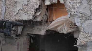 Çalışan bir adam evin duvarını bir deliciyle yıkıyor. Müteahhit özel bir elektrikli aletle duvarda bir delik açıyor. Hasarlı bir binanın yıkılması veya yeniden inşası.
