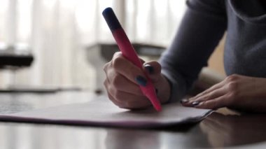 Bir kadın fosforlu kalemle bir belgede metni işaretliyor. Keçeli kalemin kadın ellerinde yakın plan çekimi. Ofis çalışanı belgelerle çalışır..