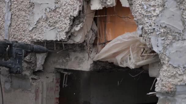 一个工人用穿孔机把房子的墙摧毁了 建筑工人用特殊的电动工具在墙上打孔 被损坏建筑物的拆卸或重建 — 图库视频影像
