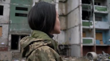 Ukrayna silahlı kuvvetleri üniformalı Asyalı kızın yakın plan portresi başını çeviriyor ve Rus ordusu tarafından yıkılan yerleşim yerlerine bakıyor. Ukrayna 'daki uluslararası askeri tabur.