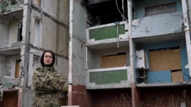 Ukrayna silahlı kuvvetleri üniformalı Asyalı kızın yakın plan portresi başını çeviriyor ve Rus ordusu tarafından yıkılan yerleşim yerlerine bakıyor. Ukrayna 'daki uluslararası askeri tabur.