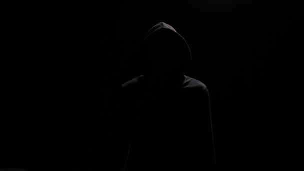 Man Zwarte Hoodie Zwarte Achtergrond Kijkt Camera Maakt Dan Gebaar — Stockvideo