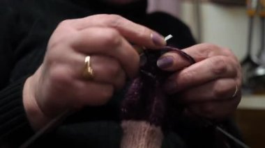 Çoraplarını yün ipliklerle ören, örgü iğneleriyle ören yetişkin bir kadının ellerine yakın çekim..
