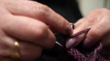 Çoraplarını yün ipliklerle ören, örgü iğneleriyle ören yetişkin bir kadının ellerine yakın çekim..