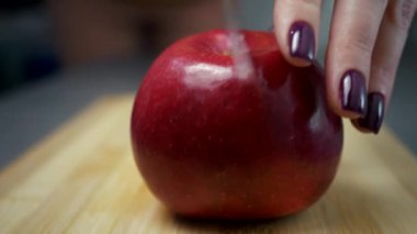 Bir kız büyük bir bıçakla kırmızı bir elmayı ikiye böler. Yakın plan. Olgun meyve kesimi. Vitamin kullanımını. Meyve diyeti..