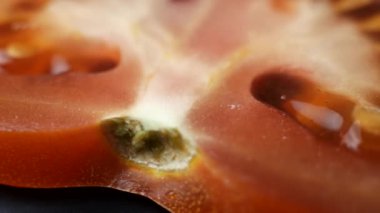 Dönen dilimlenmiş kırmızı domatesin makro çekimi. Dilimlenmiş domates diliminin dokusuna son derece yakın çekim. Taze meyve suyu..