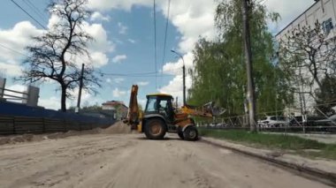 Buldozer inşaat alanında ilerliyor. Kovalı bir traktör U dönüşü yapar ve yol çalışması sırasında ata biner. Kazıcı çukur kazmaya gidiyor. Ukrayna, Chernihiv, Nisan 2023