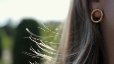 Rüzgarda savrulan bir kadının saçının yakın çekimi. Tarz sahibi beyaz bir kadının saçları rüzgarda yavaşça dalgalanır. Sığ alan derinliği.