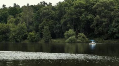 Şehir parkındaki gölde insanlar katamara biniyor. Bir grup arkadaş gölette dinleniyor. Romantik bir ortam, bir erkek ve bir kadın nehirde bir tekneyle geziyorlar..