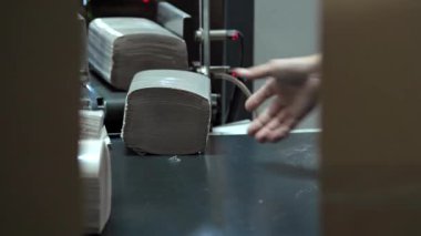 Kadın fabrika işçisi kağıt havlu ya da peçete paketlemiş. Kesme ve paketleme için taşıyıcı. Hijyenik kağıt, tuvalet kağıdı, peçete ve kağıt havlu üretiminde son aşama..
