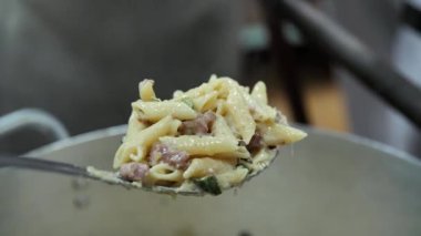 Taze pişmiş makarna, kabak, kıyma ve parmesan peyniri. Şef elinde soslu bir kaşık sıcak makarna tutuyor..
