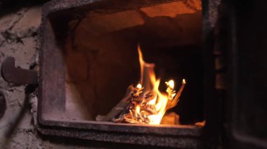 Yakın çekim şöminesi, ocağın içinde parlak bir odun alevi yakıyor. Kırmızı kömürler bir evin atmosferini ısıtır..