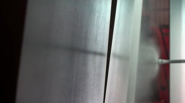 Bir işçi sprey tabanca kullanarak metal bir parçayı toz kaplamayla kaplıyor. Metal ürünlerin toz tabakası. Metalin endüstriyel renkleri. Metal yapıların fabrika tozu tabakası.