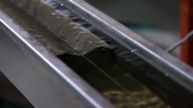 Fiberglasla sarılı optik fiber soğutma banyosundaki sudan geçer. Optik internet kablo üretim hattı. Hızlı optik veri transferi için üretim kablosu fabrikası.