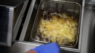 Aşçının patates kızartması ile kafesi sallayıp kızgın yağda pişirdiği en iyi manzara. Şef patatesle ızgarayı fritözün içine indiriyor. Mutfakta fast food yapma süreci. Yavaş çekim
