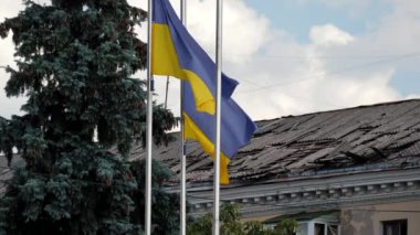 Ukrayna 'nın iki bayrağı, Rusya Federasyonu' nun füze ya da bomba saldırısı sonucu hasar görmüş bir evin arka planında dalgalanmaya başladı..