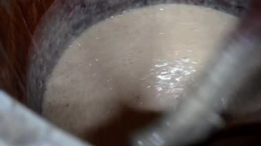 Aşçı mayalanan yaprakları bir köy varilinde ekmek pişirmek için özel bir tahta kürek veya kürekle karıştırır. Bir fırında ekmek üretimi.