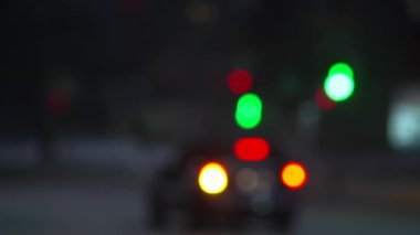 Kış karlı bir sokakta arabaların ve trafik ışıklarının bulanık ışıkları. Odaklanamayan arabalar kar fırtınasında gece şehir trafiğinden arkaplanı aydınlatıyor. Araba farlarıyla aydınlatılmış düşen kar..