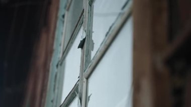 Köydeki eski ahşap bir evin camları camlı. Terk edilmiş kırsal ahşap bina. Yakın plan. Boya soyan eski bir pencerenin klasik görünümü.