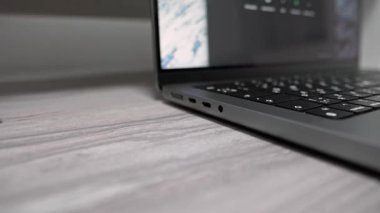 Adamın biri şarj aletini laptopa bağlıyor. Bir ağ kitabına manyetik temaslı bir şarj kablosu bağlamaya yakın çekim.