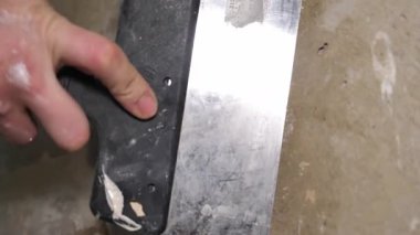 Bir sıva macunu ya da alçıyı macun bıçağıyla duvara yapıştırır. Bir adam alçıtaşlı havan topuyla elektrik dağıtım kutusunu mühürlüyor. Boyamadan veya duvar kağıdından önce duvarlar bitiriliyor.