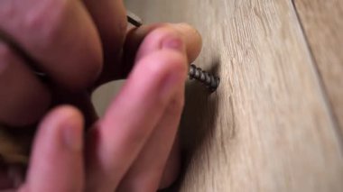 Adamın biri ya vida takıyor ya da mobilya duvarına sürgü takıyor. Büyülü anahtar ya da tornavida tutan bir adamın yakın çekimi. Bir adam evde mobilya tamir eder ya da monte eder..