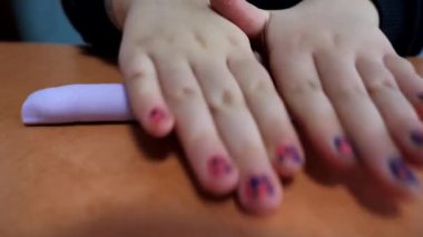 Küçük bir kız plastikle oynar, farklı şekiller şekillendirir. Çocuk masaya plastik sarar..