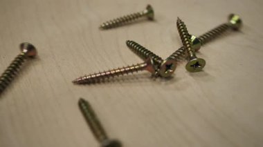 Yakın plan. Paslanmaz çelik vidalar, kazıkta bağlayıcılar. Metal montaj vidaları ahşap bir yüzeye saçılmış..
